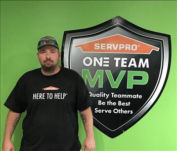 Male employee with hat by SERVPRO signage.
